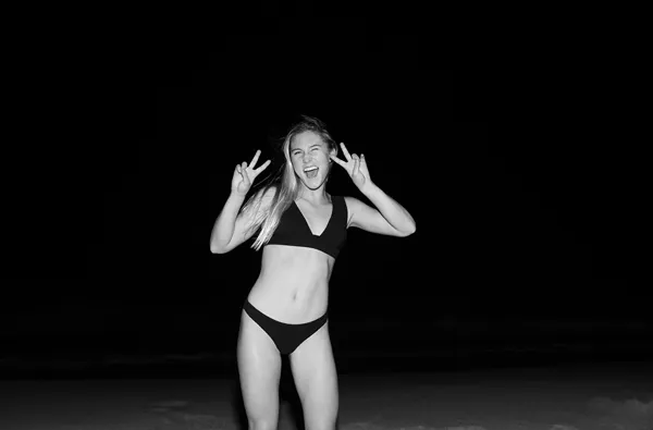 Black and white image of Alyssa Spencer holding up a peace sign. 